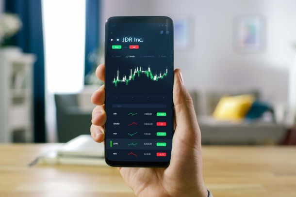 A person holding up a phone showing stock market performance.