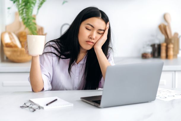 A woman falling asleep at her desk.