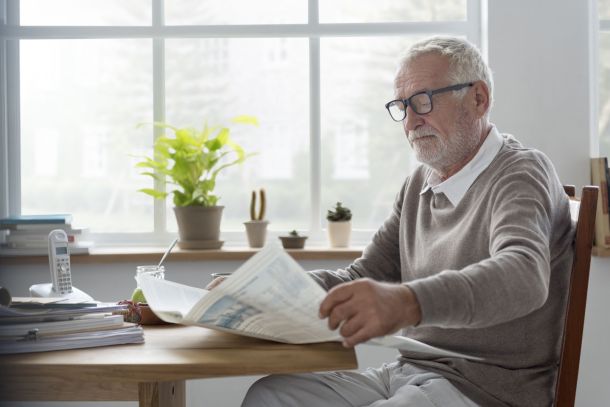 A man reading a newsletter at home.