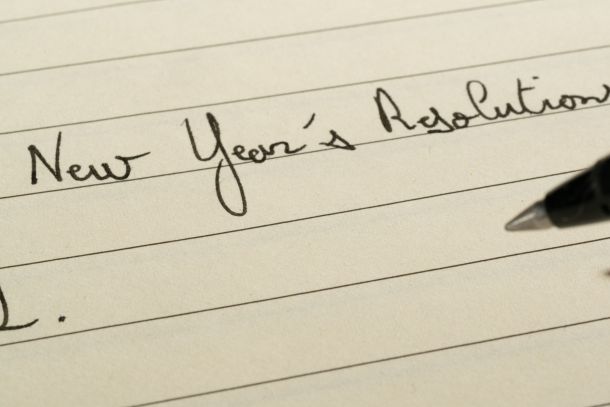 Someone writing “New Year’s resolutions” on a piece of paper.
