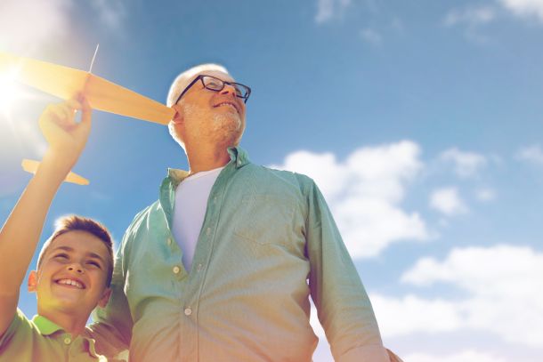 A grandfather and grandson playing with a toy plane outdoors.