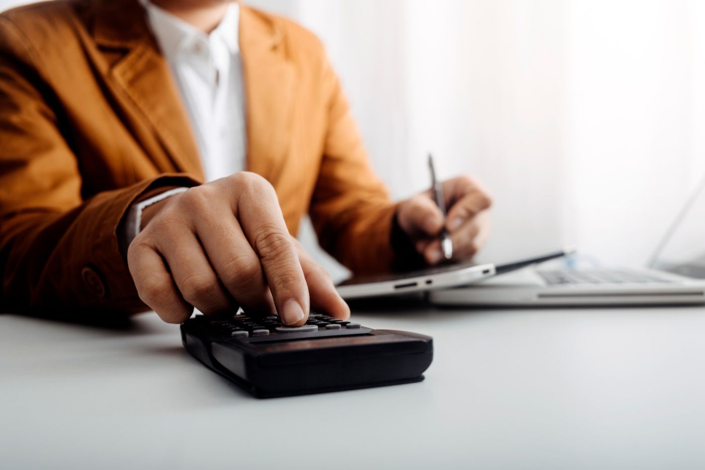 A business owner using a calculator at a desk.