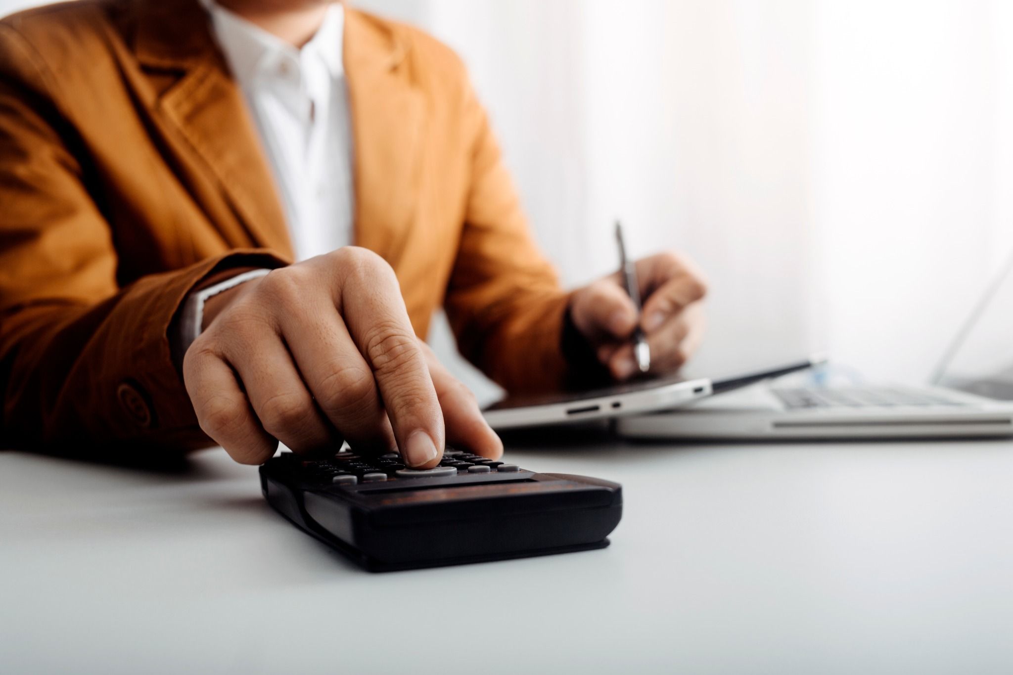 A business owner using a calculator at a desk.